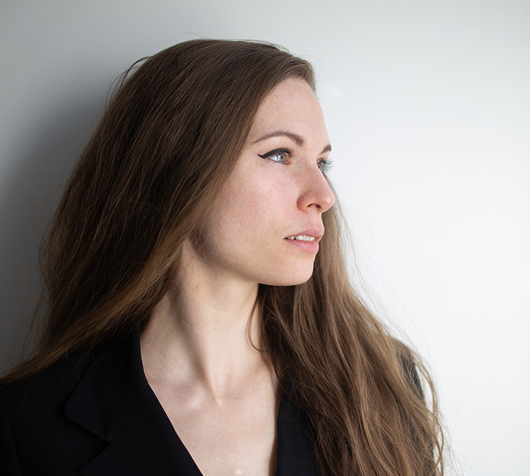 profile of face of female with long brown hair in black v-neck top.