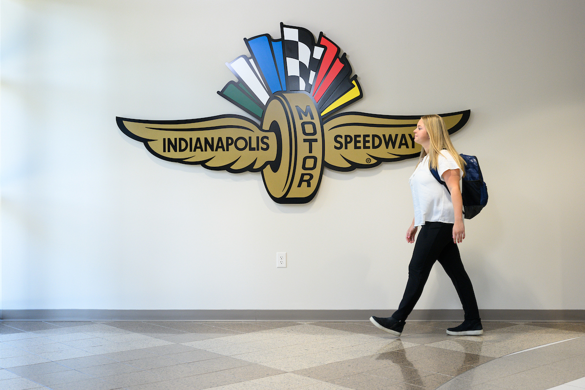 Image of person in front of the Indianapolis Motor Speedway sign