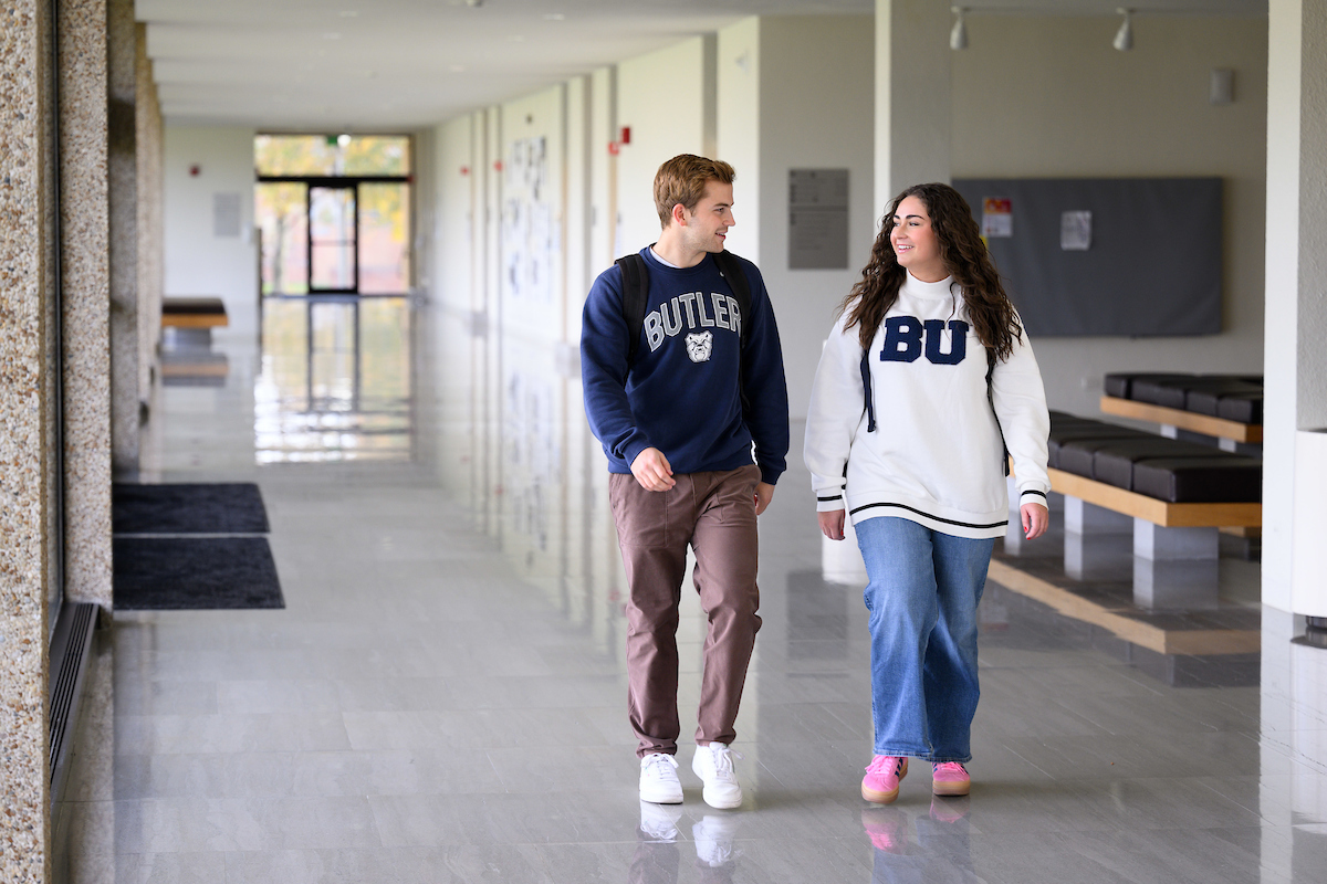 Two students walk together in a hallway.